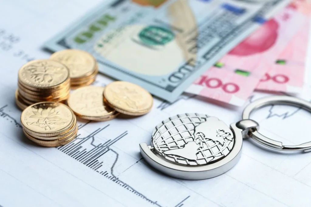 Coins and banknotes on a financial chart with a globe keychain, illustrating global finance at a glance.